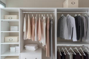modern closet with clothes hanging on rail, white wooden wardrobe, interior design concept